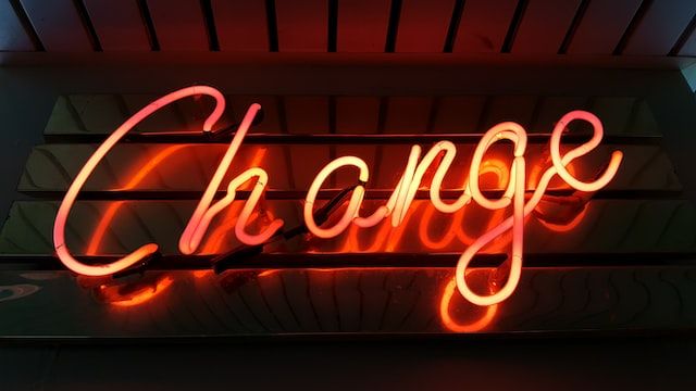Lighted orange neon sign saying Change in front of dark background
