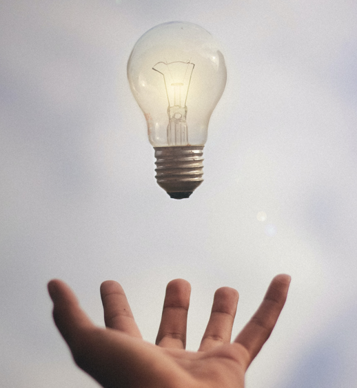 A lightbulb floating in the air several inches above an open hand