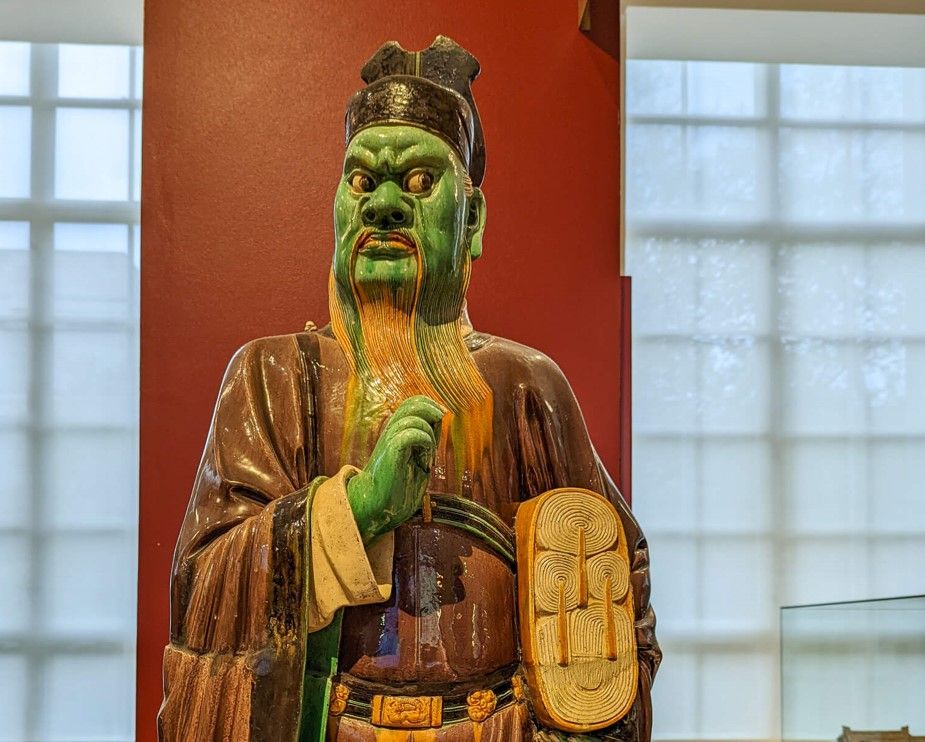Statue of green-colored scholar with disdainful expression