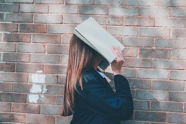 Woman covering her face with a book