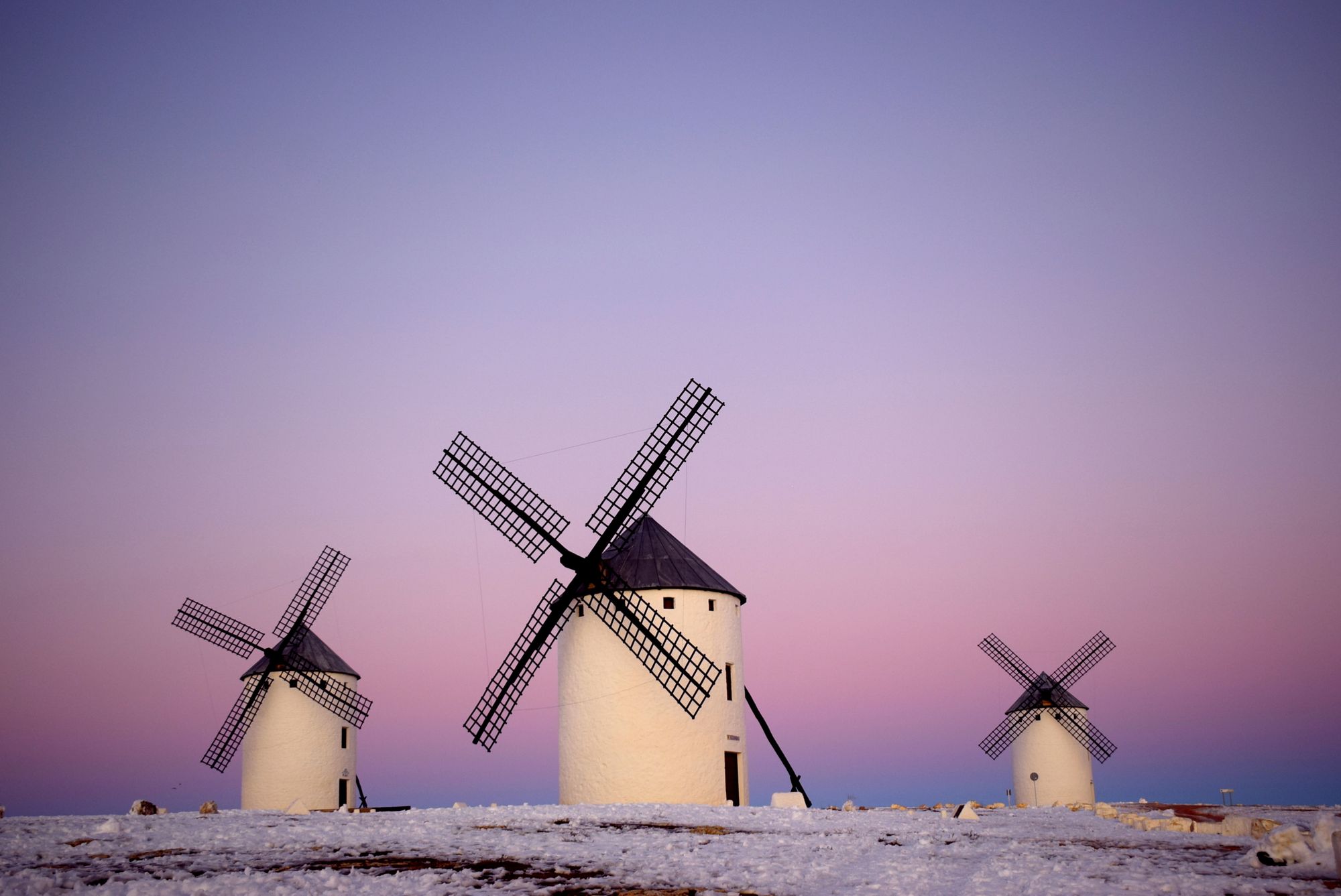 Three windmills against a purple sky