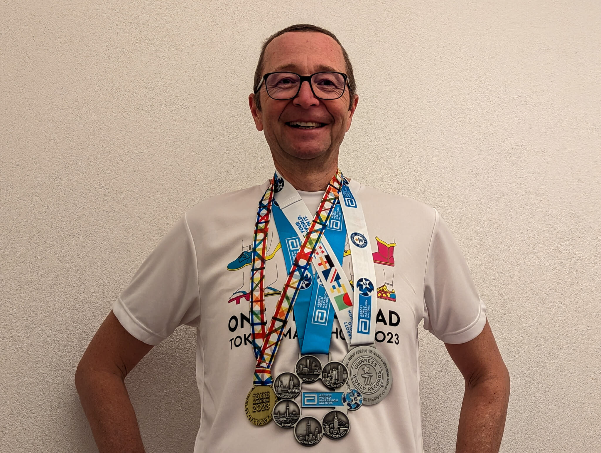 Author with Toyko Marathon finisher shirt & medal, plus six star medal and world record medal