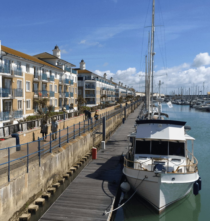A powerboat docked in a marina alongside a row of apartments