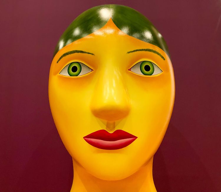 Large painted yellow head with green hair, green eyes, and red lipstick