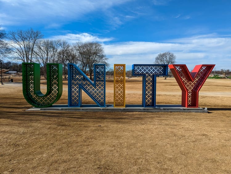 Large metal sign in a field reading U N I T Y