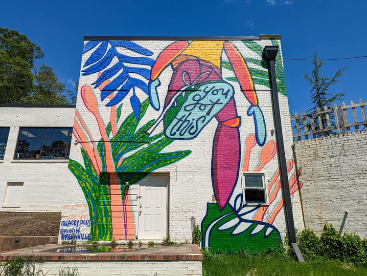 A mural of a standing man with a raised foot saying "You got this" on the sole