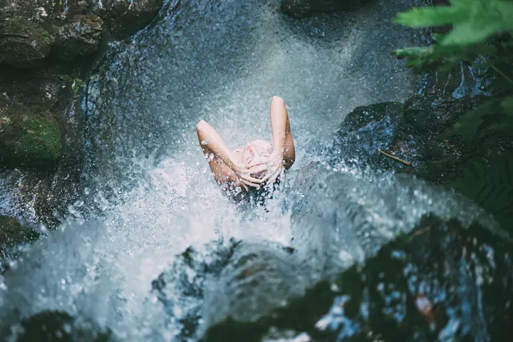 Woman bathing under a waterfall