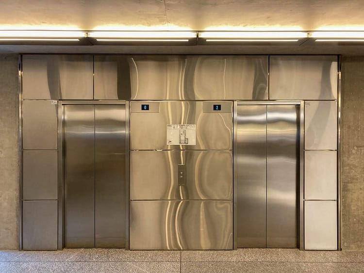 Two stainless steel elevator doors on a shiny metal wall