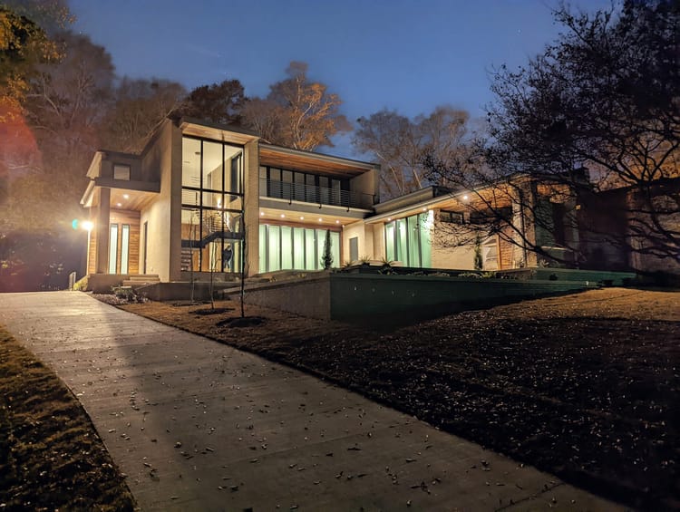 A beautiful modernist house at night, glowing from internal lights