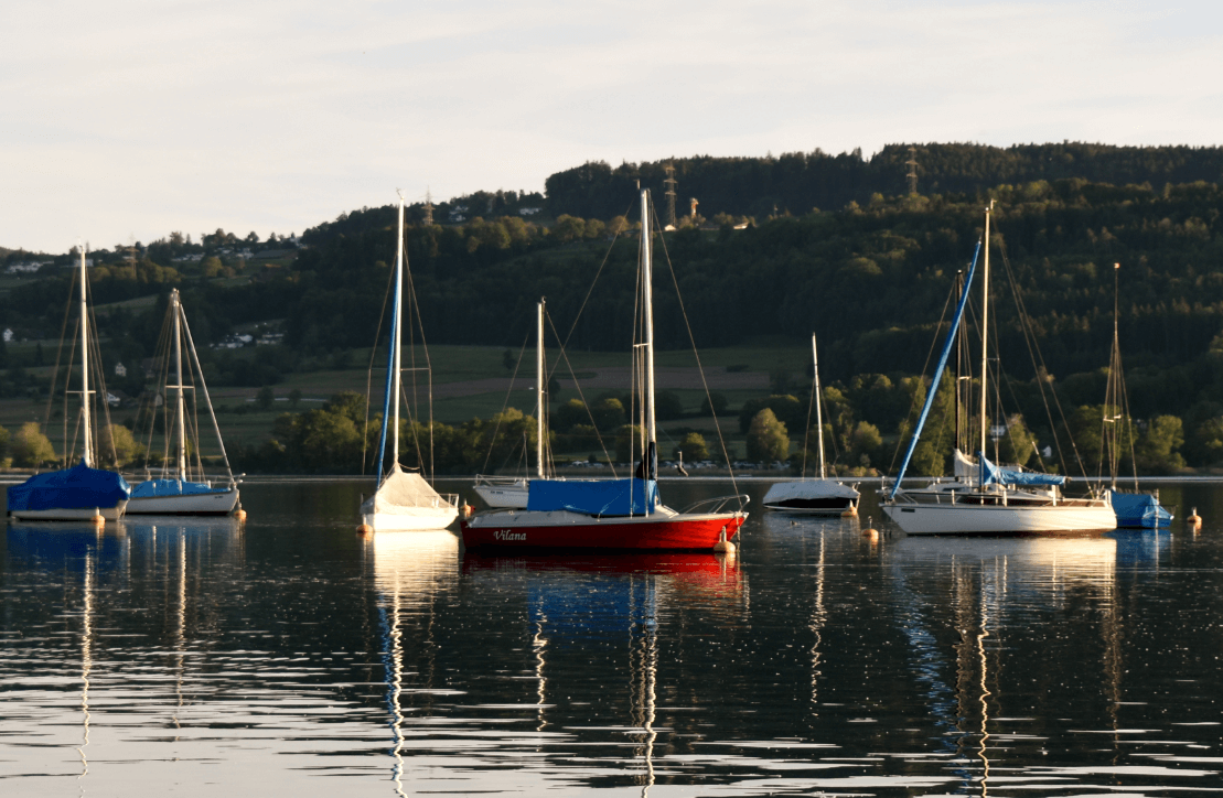 Red, white, and blue sailboats on a calm lake - Moral Letters to Lucilius