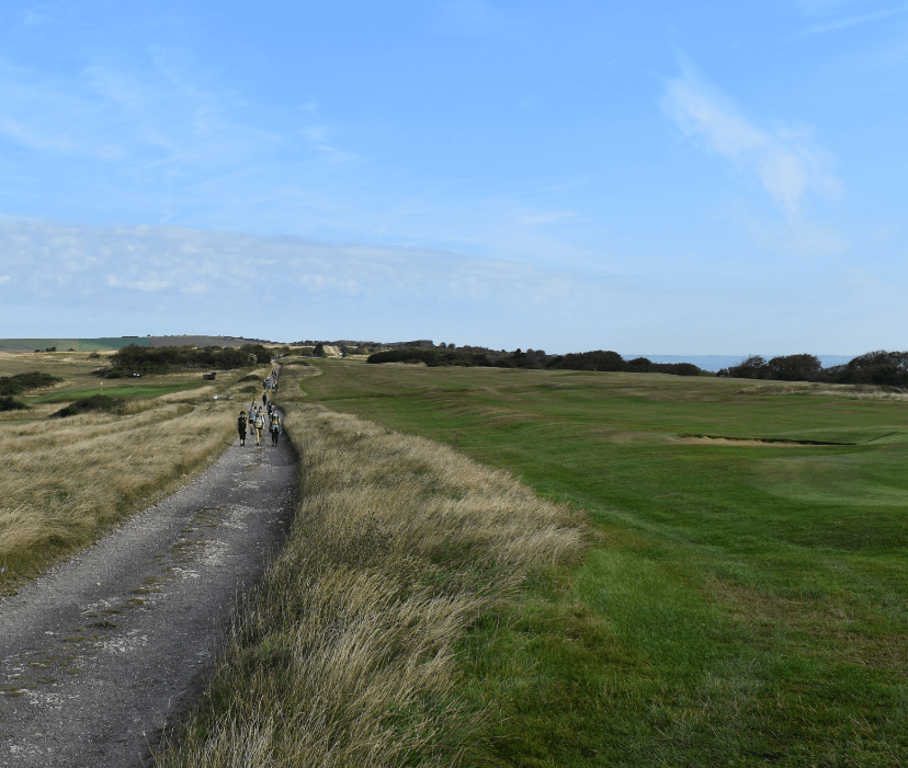 Trail with hikers walking alongside grassy fields - Moral Letters to Lucilius