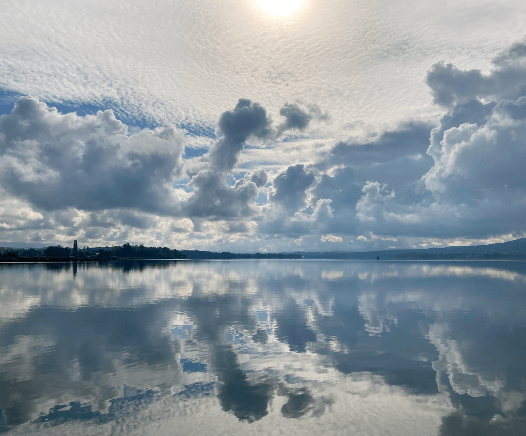 Large lake with clouds and sky perfectly mirrored in the water