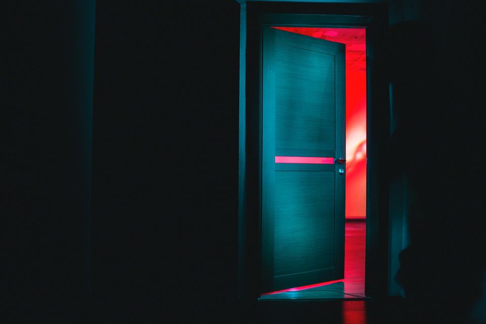 Dark wall with a dark door opening onto a vivid red background