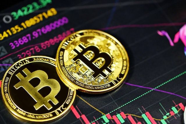 Two gold bitcoins lying atop a trading screen