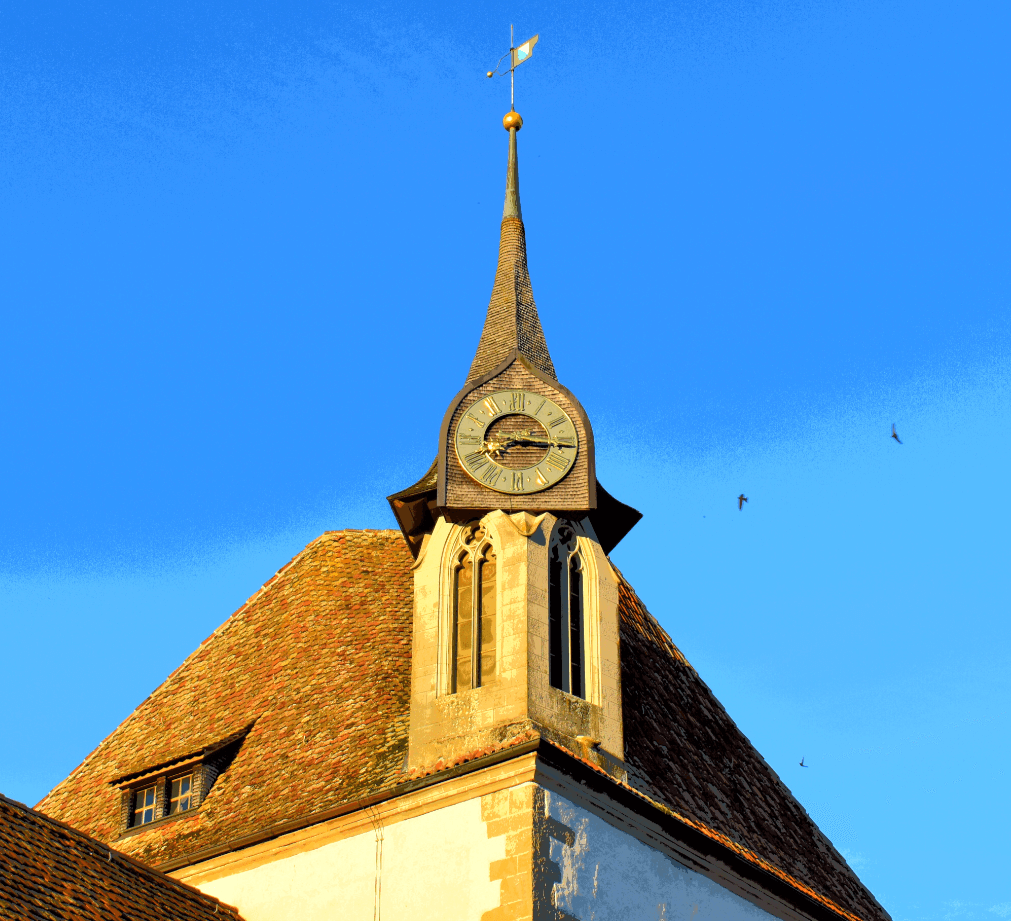 Church spire in bright sunlight before a blue sky