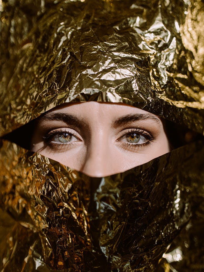 Woman’s eyes looking out of a gold foil background