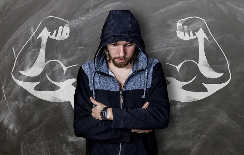 Man standing before chalkboard with drawing of large biceps