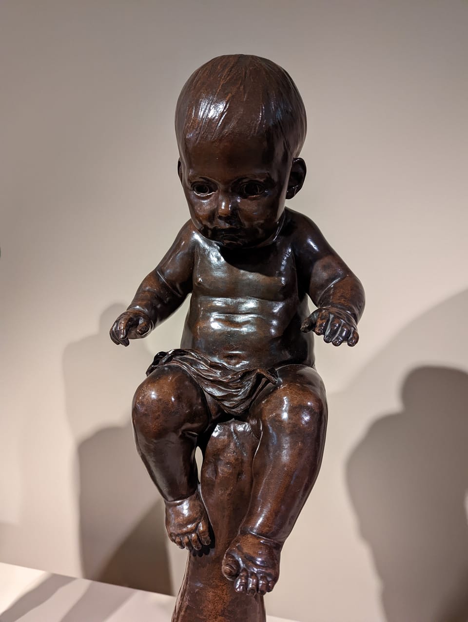 Sculpture of a baby sitting on an upturned hand - wishful thinking is the province of children