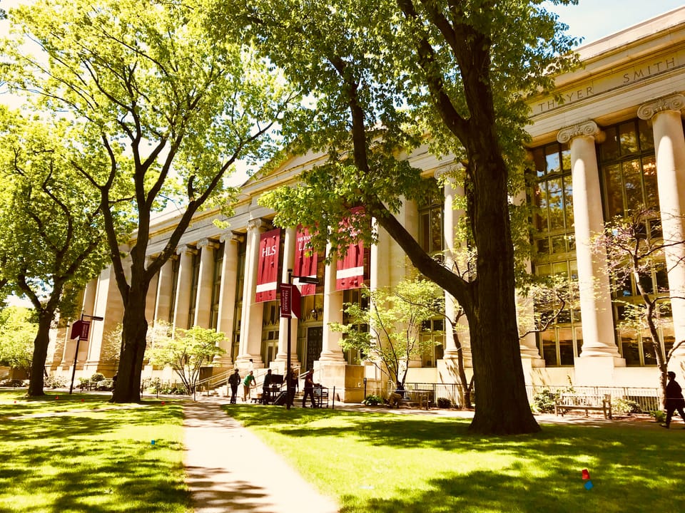 University facade of Harvard Law School, with green lawn and trees in the foreground